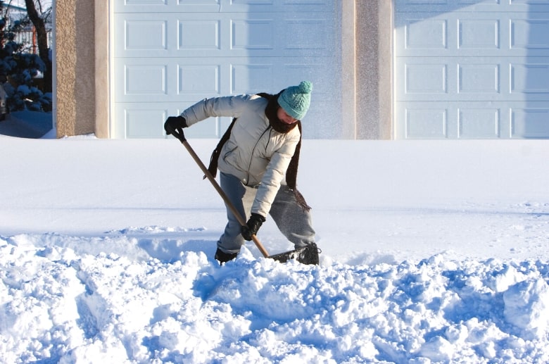 Clear the snow by shoveling it away from the garage door frozen shut.