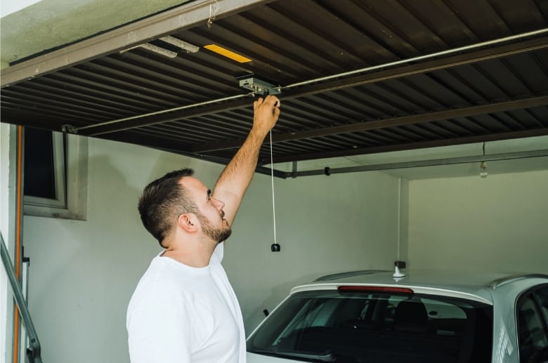 A man opening a garage door manually.
Manually opening the garage door is one of the ways to bypass garage door sensor.