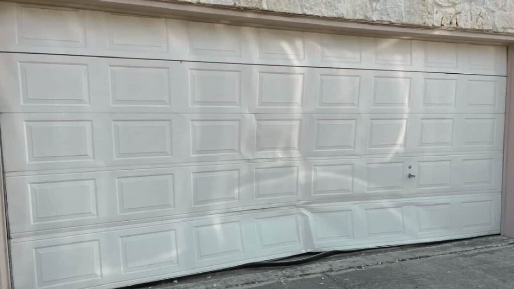 A dented garage door that needs a garage door dent repair technician.