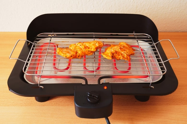 An electric grill with food. You can use it when grilling in garage.