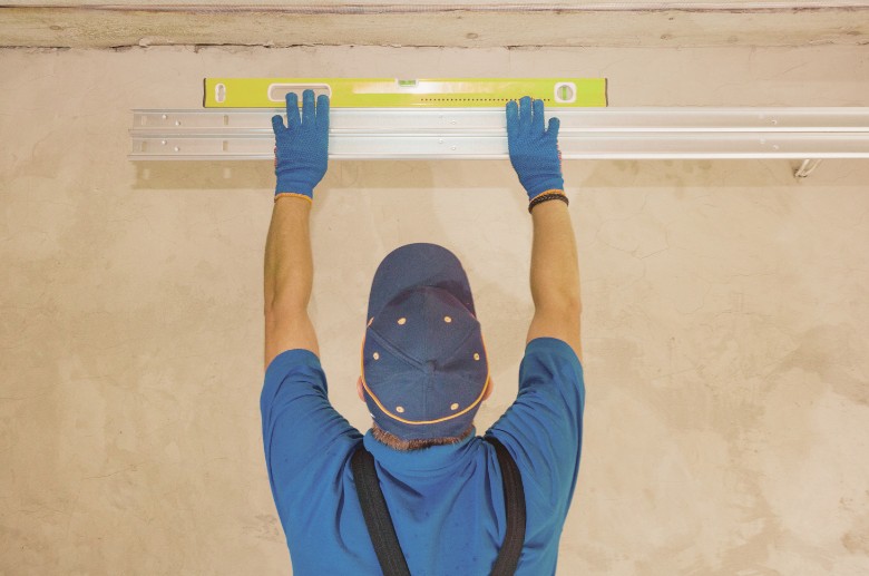 A technician is checking if the tracks are aligned. This is the  first part to check if your garage door jerks when closing.