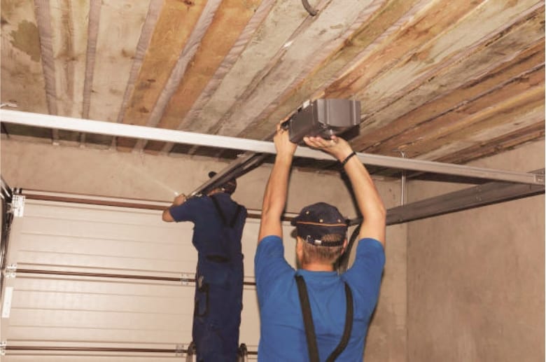 Technicians are fixing a garage door opener. This is one of the parts to check if your garage door jerks when closing.