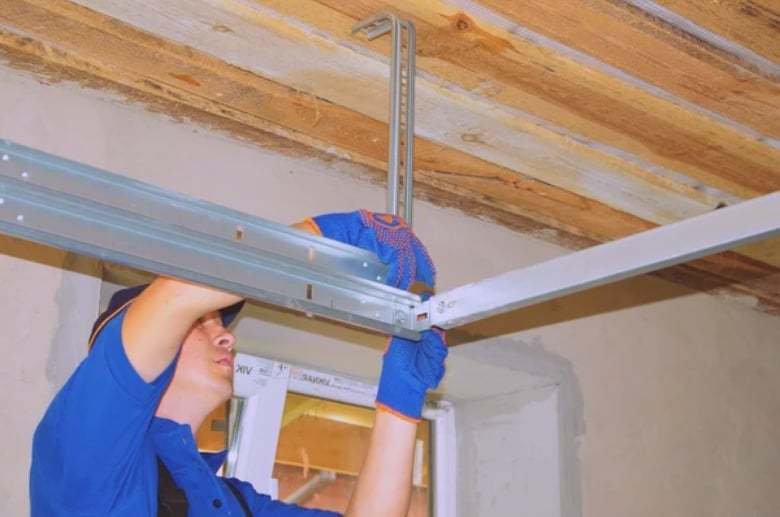 A technician is fixing a garage door track. A garage door clicking can be caused by a misaligned track.