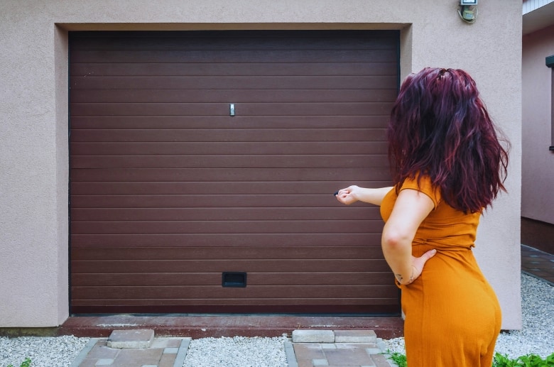 A woman trying to open a garage door.