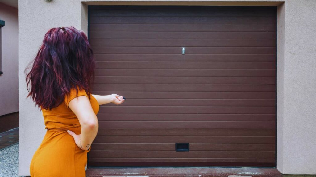 A woman trying to open when then garage door is stuck.