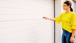 A woman opening a garage door. Know how to make garage door quiet when opening it or closing it.