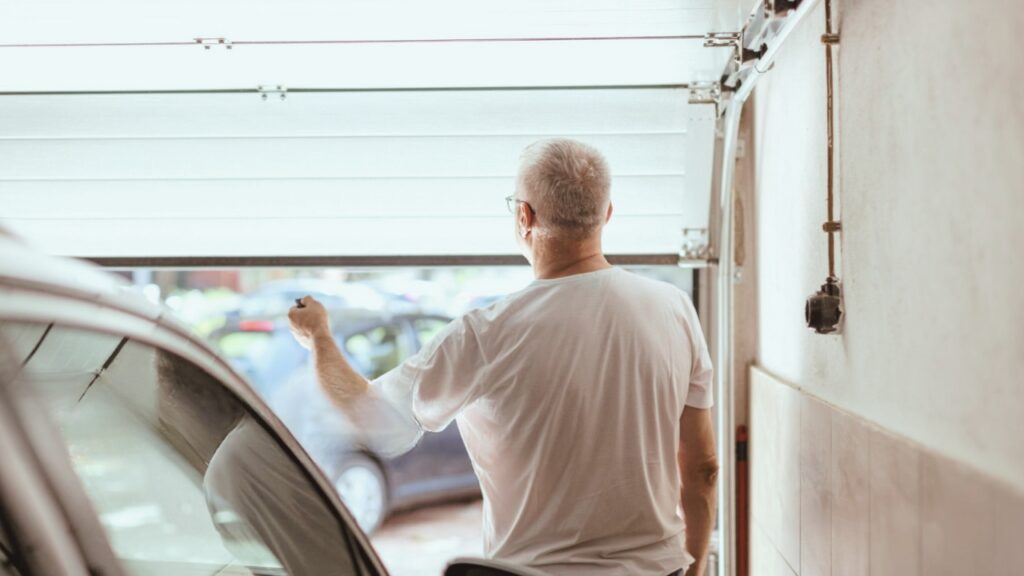 A man opening a garage door. Know the steps to fix when your garage door motor keeps running.